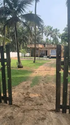 a house with palm trees in front of a field at Casa Ganesha beach villa in Irimbranallūr