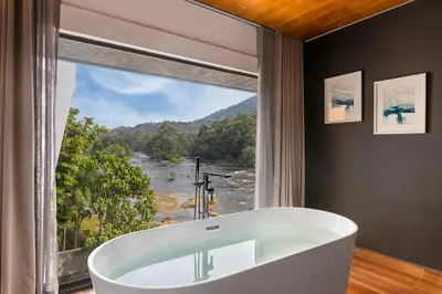 a bath tub in a bathroom with a large window at Sterling Athirappilly in Athirappilly
