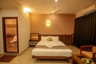 a bedroom with a large bed and a bathroom at ARIAT AVENUE in Wayanad