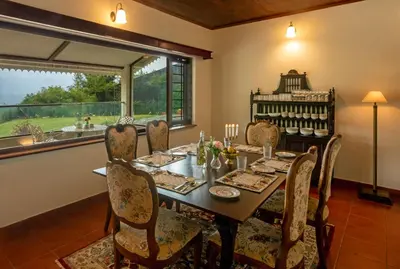 a dining room with a table and chairs and a window at Emerald by Nature Resorts and Stays in Ooty