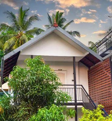 a house with a balcony and a tree at Farm Fort Resort in Kozhikode