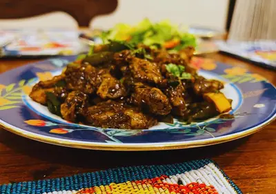 a plate of food with meat and vegetables on a table at Wild Pastures by Nature Resorts and Stays in Masinagudi
