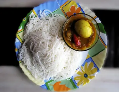 a plate with noodles and a bowl of food at CITADEL HOLIDAY HOME in Vythiri