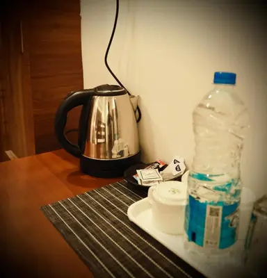 a tea kettle and a bottle of water on a table at Silverstone Inn in Nedumbassery