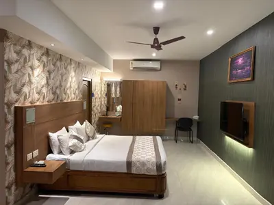 a hotel room with a bed and a television at Hotel Mangala Temple View in Guruvāyūr