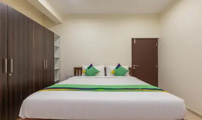 a bedroom with a large white bed with green pillows at Treebo Samanvaya Retreat, Mysore in Mysore