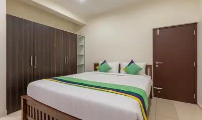 a bedroom with a large white bed with green pillows at Treebo Samanvaya Retreat, Mysore in Mysore