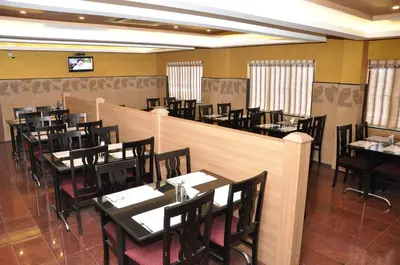a restaurant with tables and chairs and a bar at Hotel Royal Chambers in Coimbatore