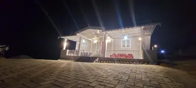 a white house at night with a brick driveway at Sky High Villa - Premium Cottages in Ooty