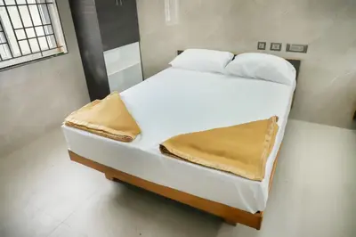 a large white bed in a small room at Viruksham Residency in Palani