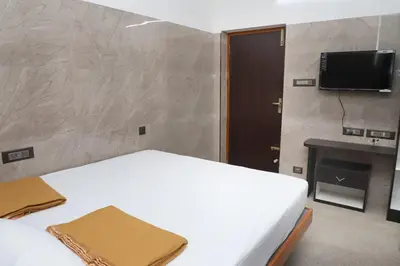 a bedroom with a white bed and a television at Viruksham Residency in Palani