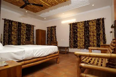 a bedroom with a bed and a chair and curtains at The Alpine Inn in Gūdalūr