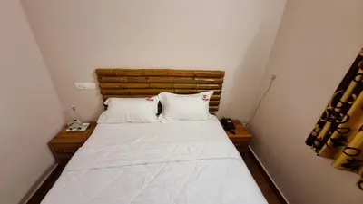 a bed with two pillows in a small room at The Alpine Inn in Gūdalūr