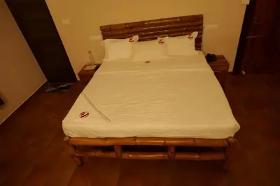 a bed with a wooden headboard and white sheets at The Alpine Inn in Gūdalūr