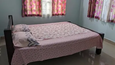 a bed in a bedroom with a pink bedspread at Delight Homestays Coorg in Kushālnagar