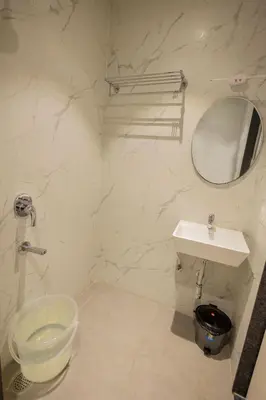 a white bathroom with a sink and a mirror at HOTEL VARDHA Inn in Bhavāni