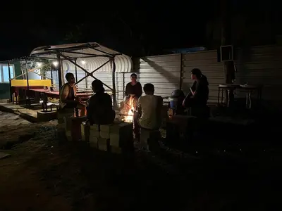 a group of people standing around a fire at night at The Wild Farms By Gwestai in Masinagudi