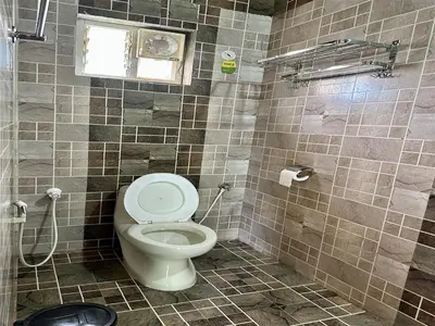 a tiled bathroom with a toilet and a window at The Wild Farms By Gwestai in Masinagudi