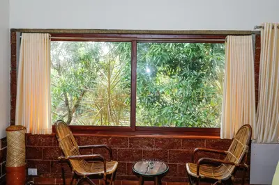 a room with a large window with two chairs and a table at Neelambari Ecotoursm in Trichūr