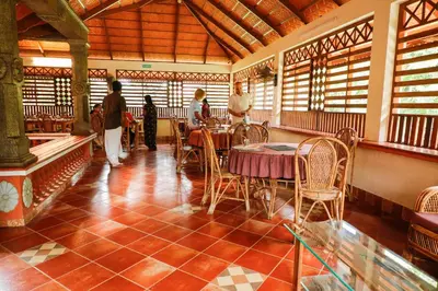 a restaurant with tables and chairs and people walking around at Neelambari Ecotoursm in Trichūr