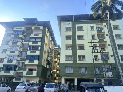 a tall building with cars parked in front of it at Soorya Madhavam Apartment Guruvayur - 200 m from temple walkable in Guruvāyūr