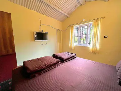 a bedroom with a bed and a tv on the wall at VERMONT HOMe STAY in Ooty