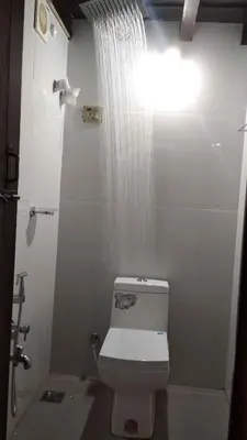 a bathroom with a shower and a toilet with a waterfall at River view cottage in Vythiri