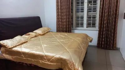 a bed with a gold comforter and a window at Niks home stay - A in Trichūr