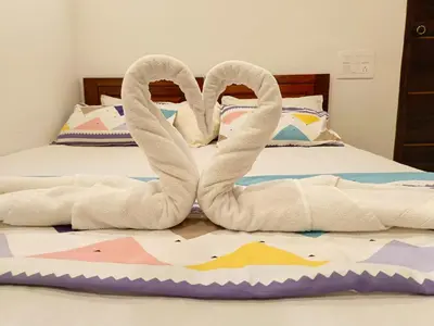 two towel swans sitting on top of a bed at Paradise Single Room in Wayanad