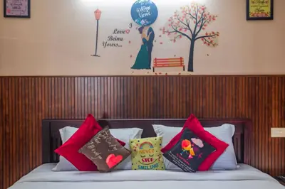 a bed with colorful pillows on top of it with a wall at Sancta Maria Airport Hotel in Cochin