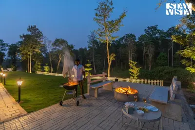 a man standing on a patio with a grill at Stayvista at Mudra Manor 4BR - Coffee Estate Comp Breakfast Big Heated Pool in Madikeri