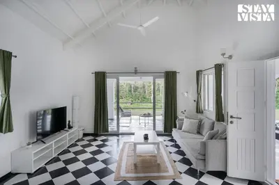 a living room with a couch and a tv at Stayvista at Mudra Manor 4BR - Coffee Estate Comp Breakfast Big Heated Pool in Madikeri