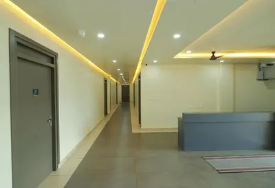 a corridor of an office building with a hallway with lights at RIVULET HOTEL APARTMENTS in Mukkam