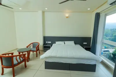a bedroom with a bed and a table and chairs at RIVULET HOTEL APARTMENTS in Mukkam