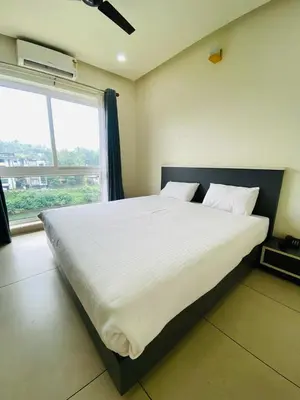 a large bed in a room with a large window at RIVULET HOTEL APARTMENTS in Mukkam
