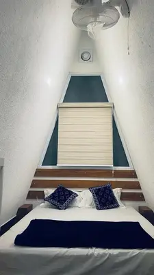 a bed with two blue pillows in a room at The Mallika Holidays - A Cabin in Mananthavady