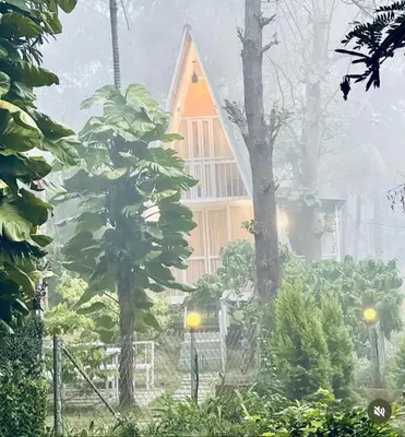 a house in the rain with trees in front of it at The Mallika Holidays - A Cabin in Mananthavady