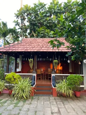 a house with a table and chairs in front of it at Dove cottage in Cherai Beach