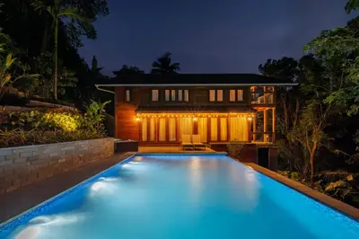 a swimming pool in front of a house at night at amã Stays and Trails The Malabar Villa Hibiscus, Kozhikode in Puthuppādi