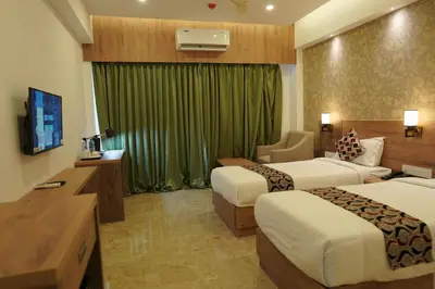 a hotel room with two beds and a television at HOTEL VKJ INN Aluva in Alwaye