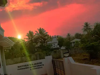 a rainbow in the sky over a house with a building at MATHER RAJAGIRI FURNISHED APARTMENTS in Alwaye
