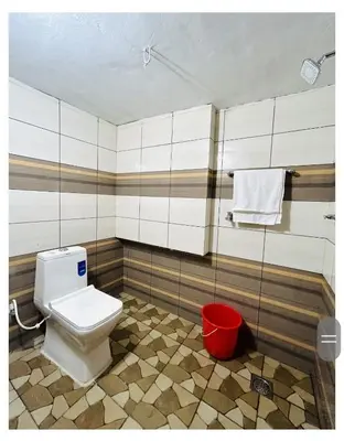 a bathroom with a toilet and a red bucket at 4 Bedroom Jungle Villa in Panamaram