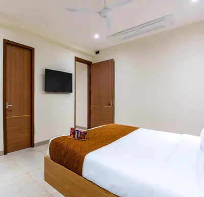 a bedroom with a bed and a tv on the wall at HOTEL ACHYUT in Tiruppūr