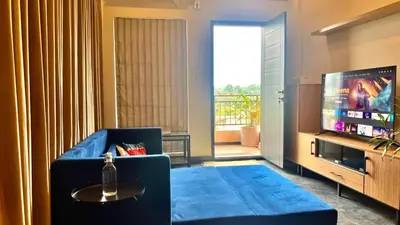 a living room with a blue couch and a tv at Green Horizon, Luxury & Nature at Kothamangalam in Kotamangalam