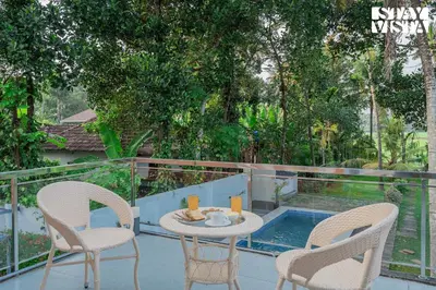 a patio with a table and two chairs and a pool at StayVista at Nature Nook with Pvt Pool & Terrace Access in Trichūr