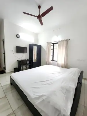 a bedroom with a large white bed with a ceiling fan at Olive Homestay 1bhk Diamond Ernakulam in Alwaye