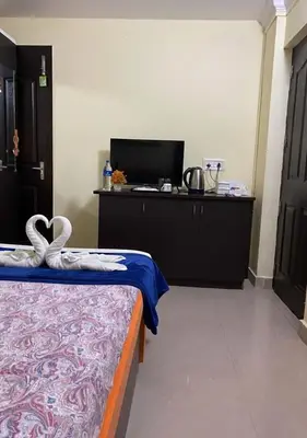 a room with a bed and a desk with a computer at Joys Stay in Trichūr