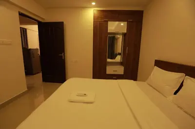 a bedroom with a white bed with a mirror at VVP serviceapartments cochin Airport in Nedumbassery