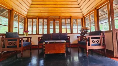a room with two chairs and a table and windows at Moksha The blissful escape in Kaniyāmbetta