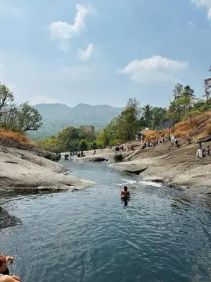 a person standing in the water in a river at Maskan Home Stay in Kakkadampoyil